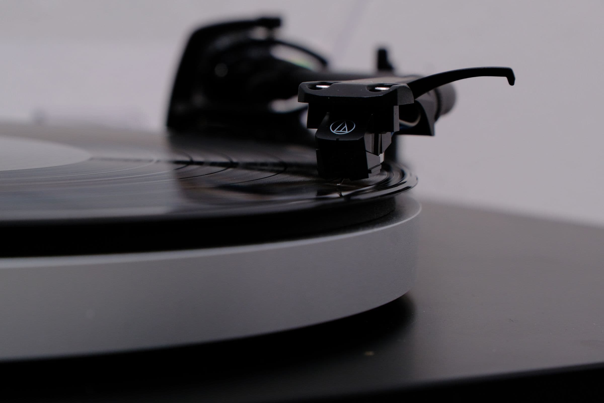 Turntable needle resting on a vinyl record, close up