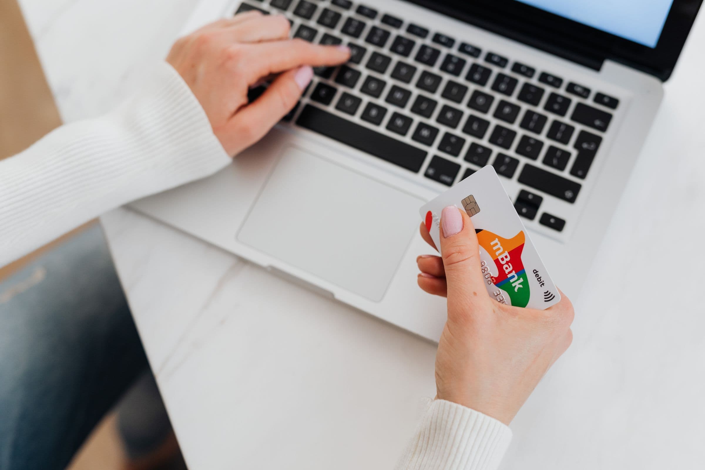 Hands holding a credit card over a laptop keyboard