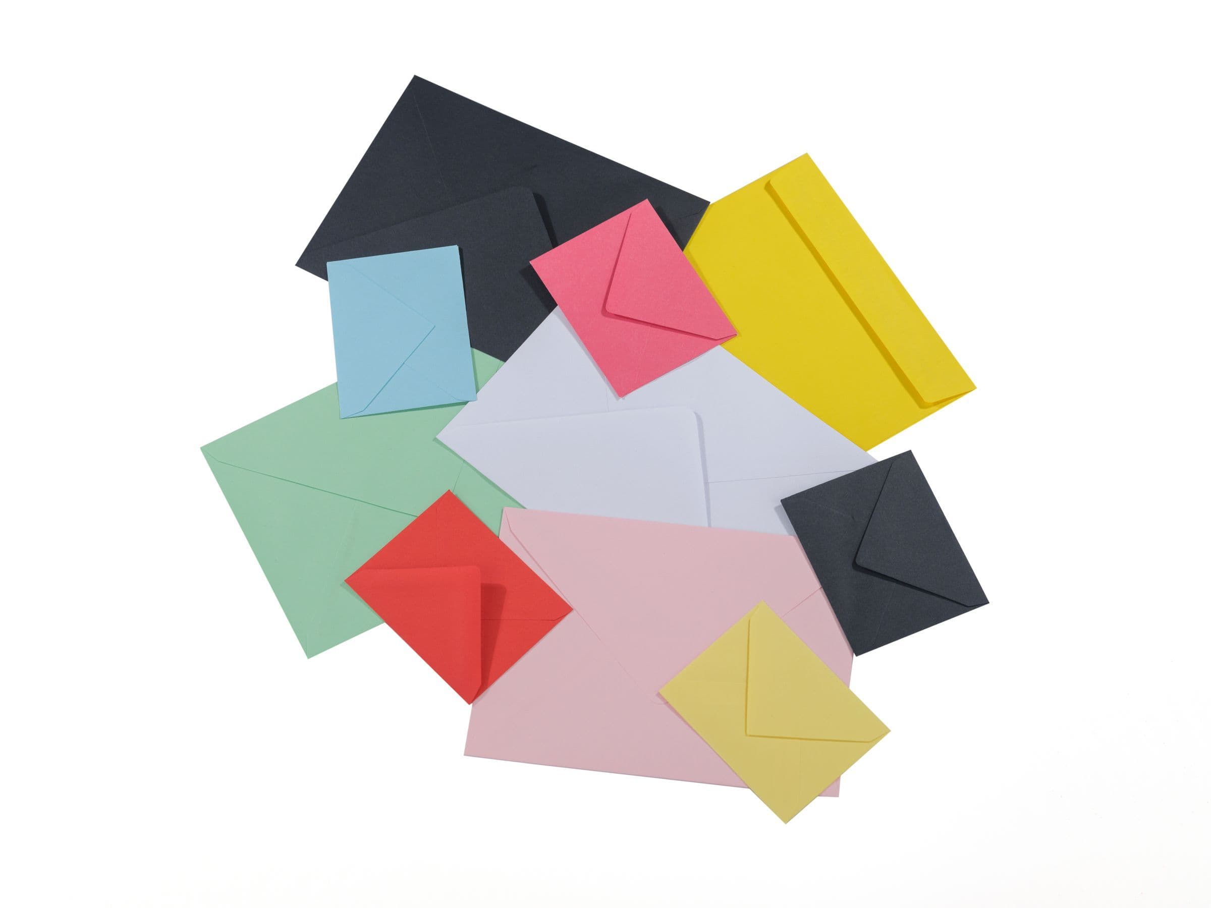 Colorful paper envelopes of different sizes scattered on a white surface