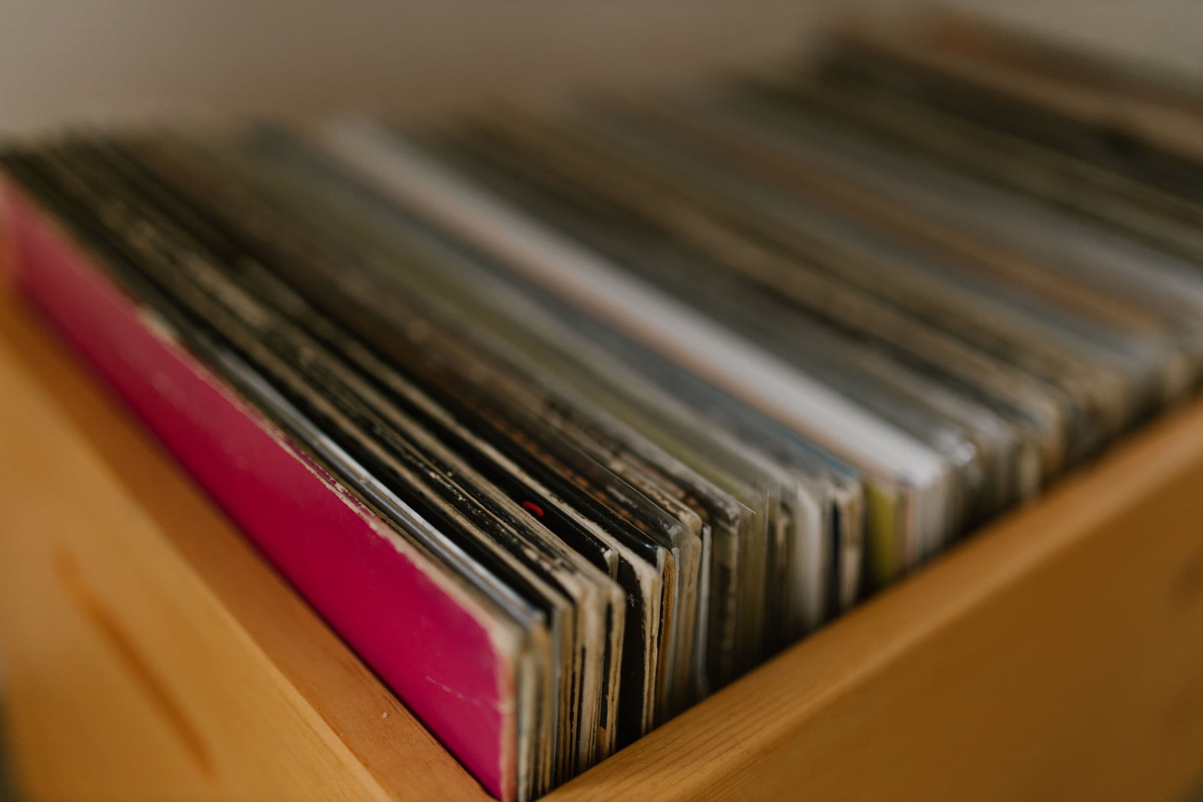 Row of vinyl records standing in a wooden crate, shot close up