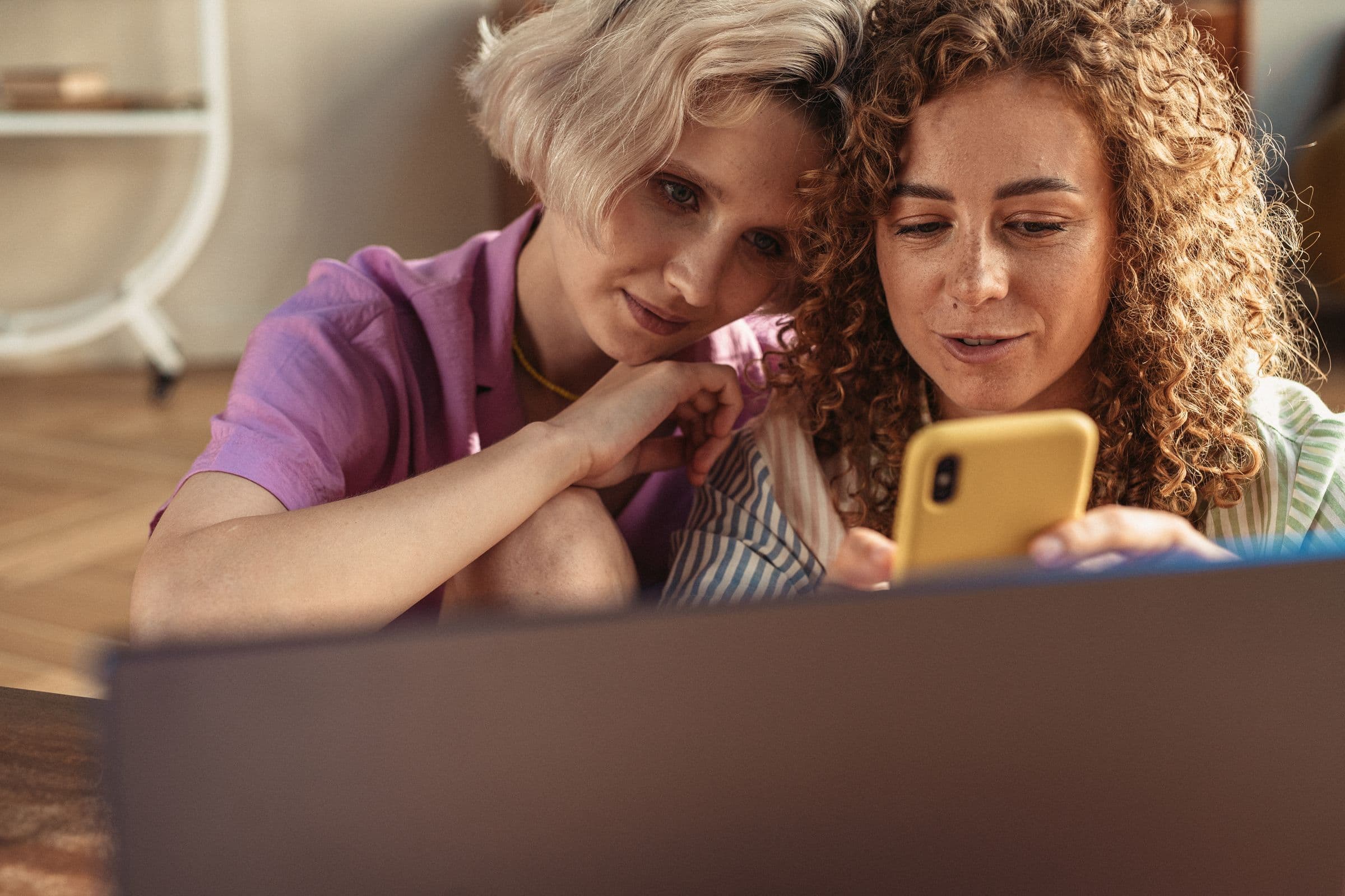 Two women on a sofa looking at a smartphone together