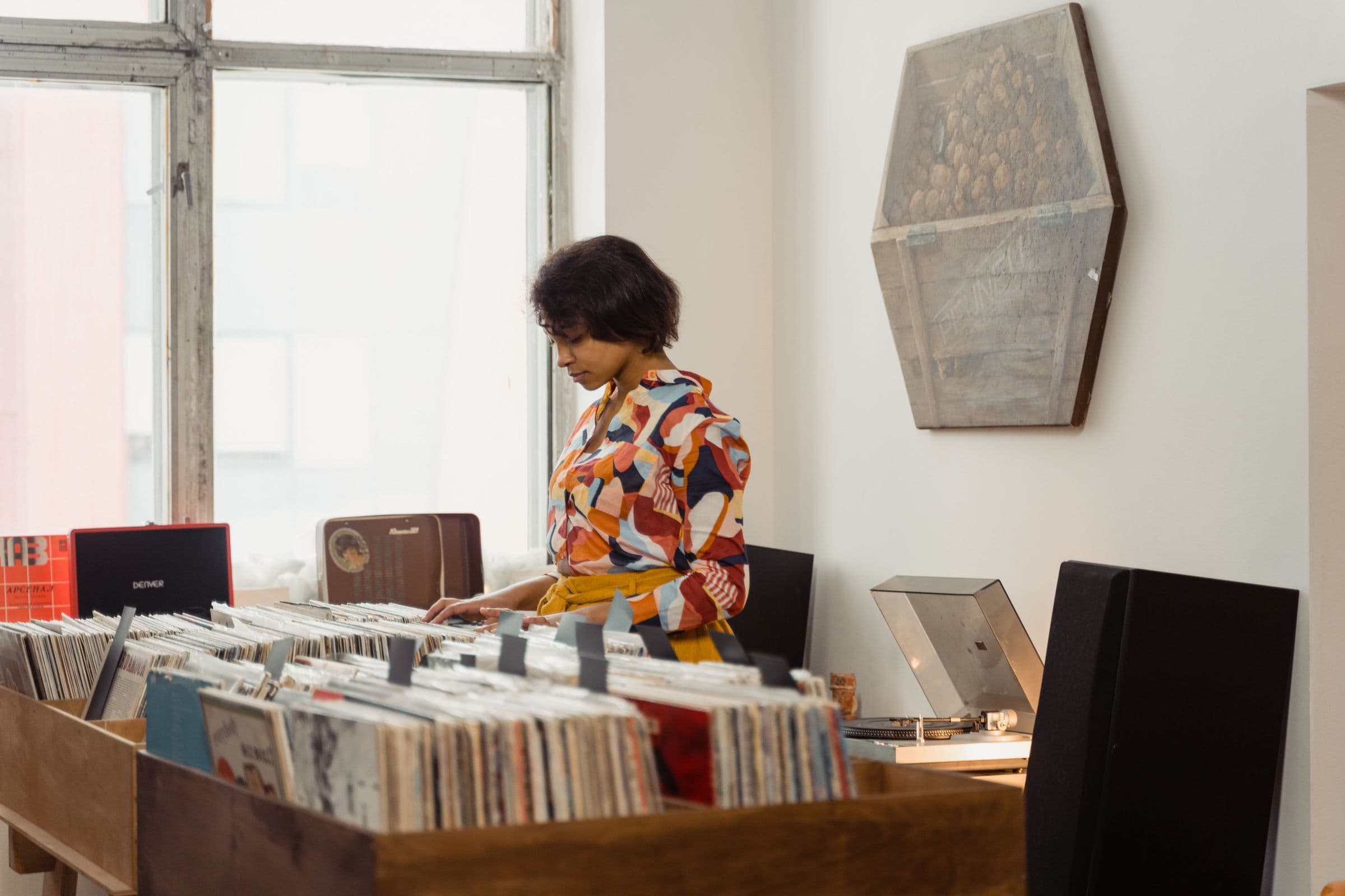 Woman in a colorful shirt looking through vinyl records in a music store