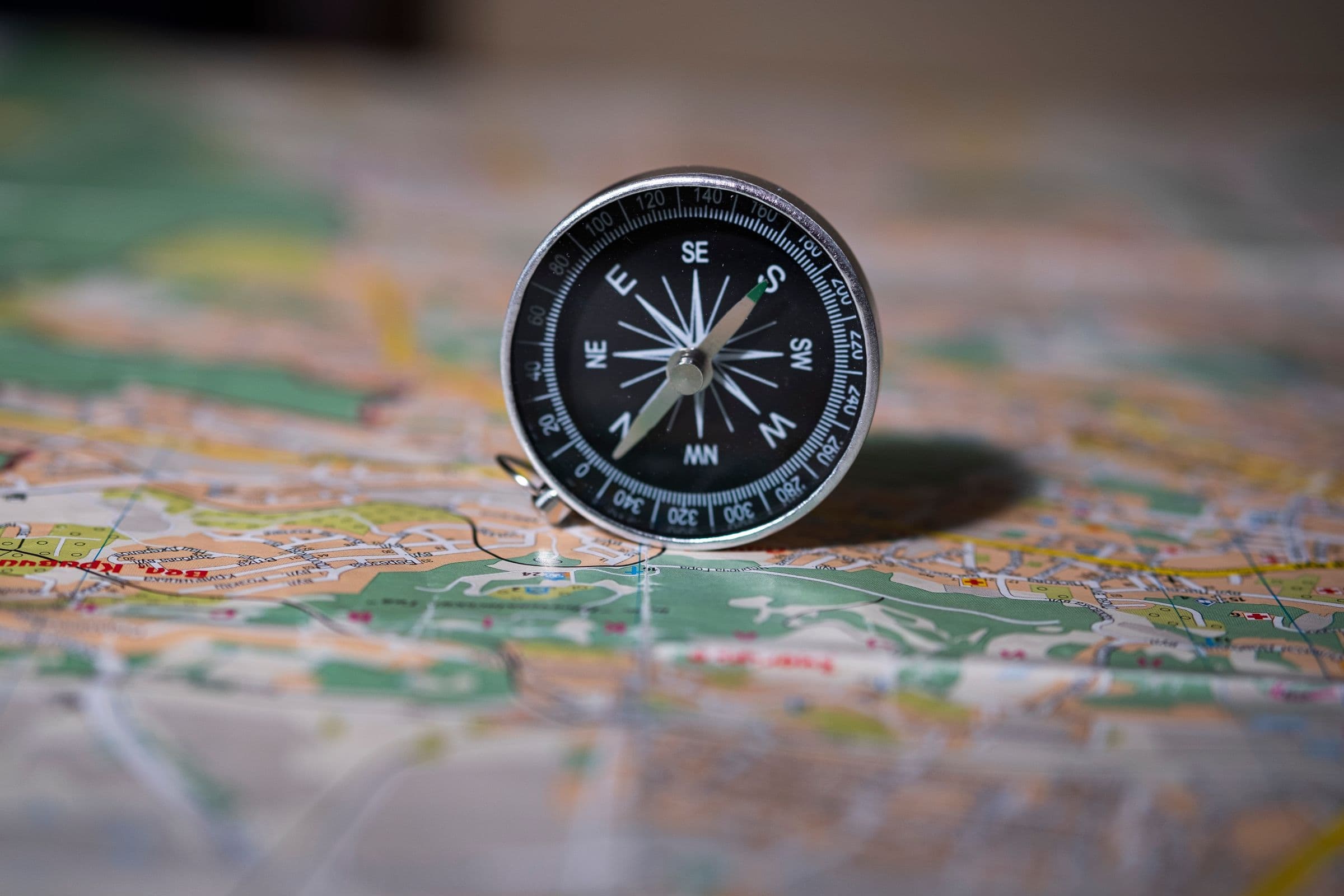 Black compass resting on a detailed paper map