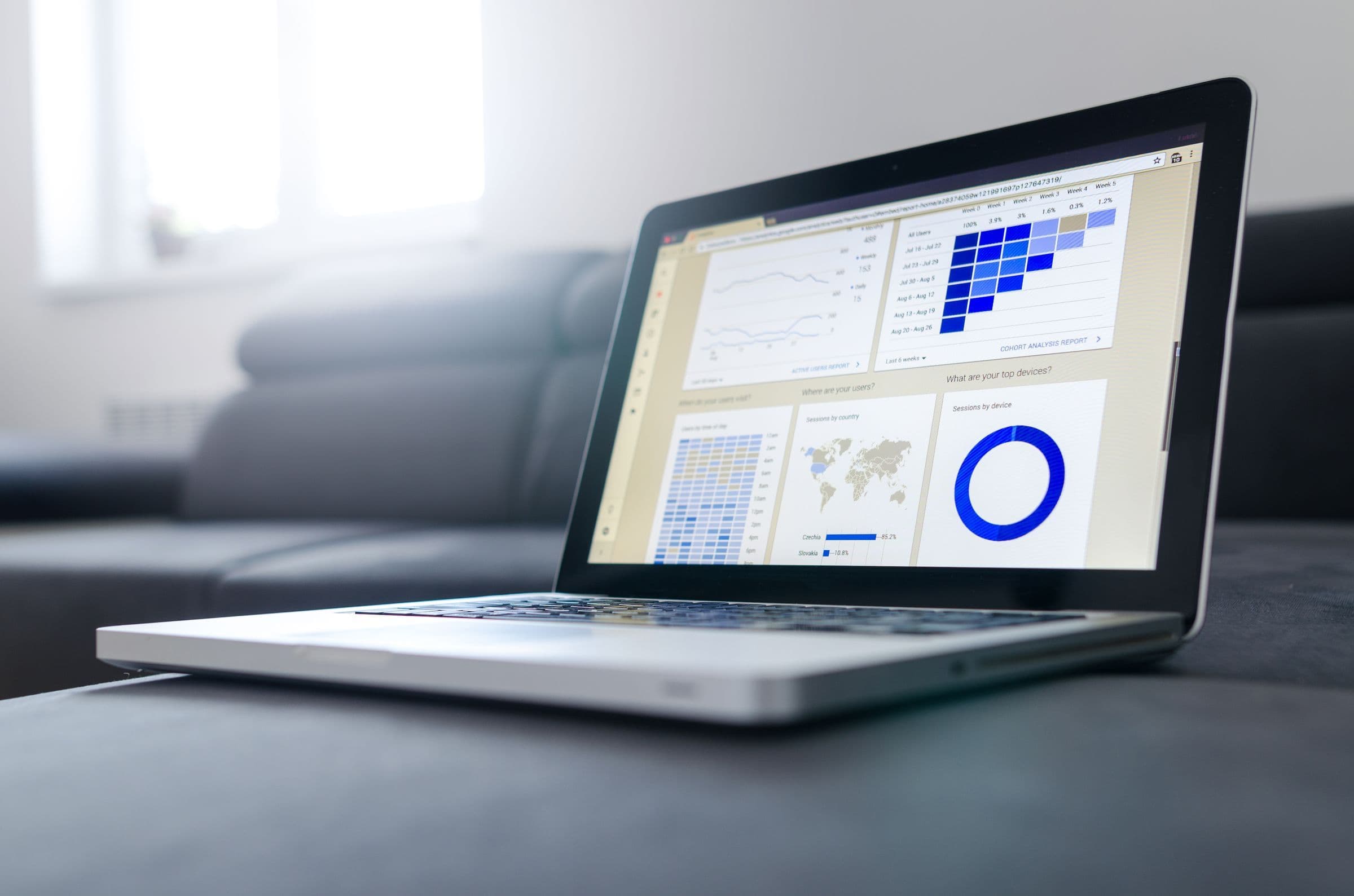Laptop on a gray sofa showing a dashboard of charts and graphs