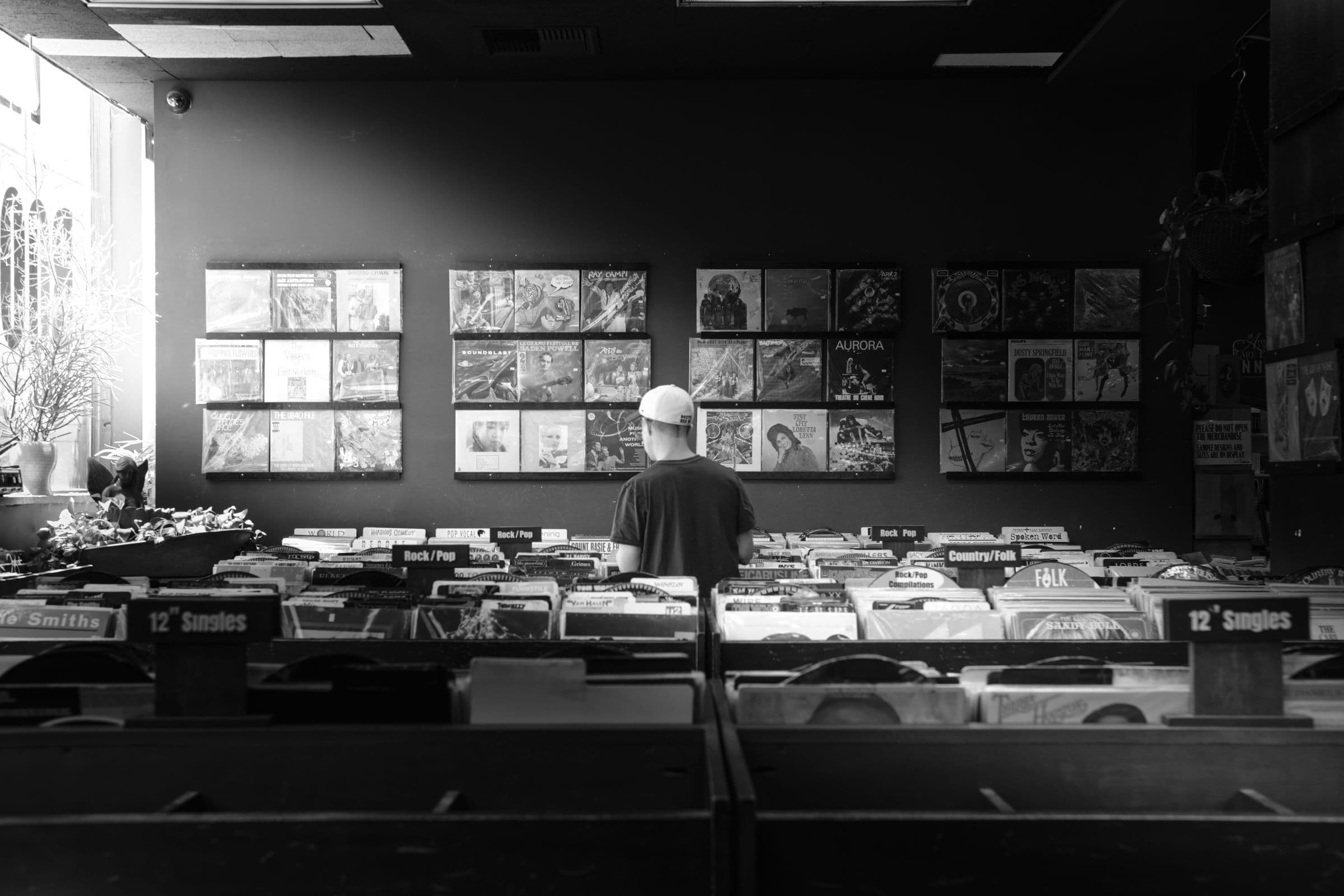Young man in a cap browsing crates of vinyl records in a record store