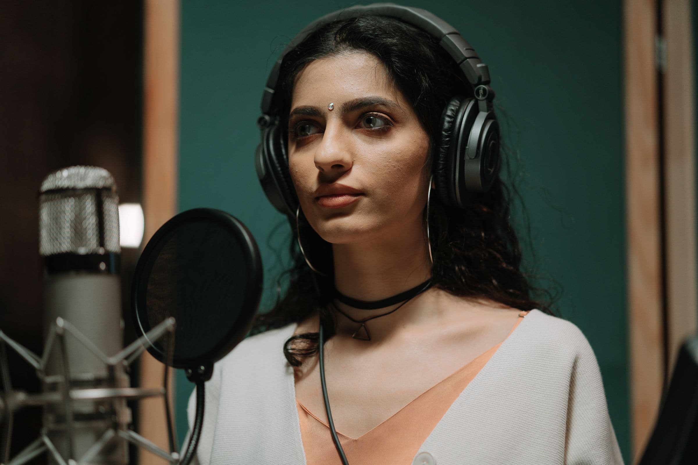 Singer in headphones at a studio microphone with a pop filter