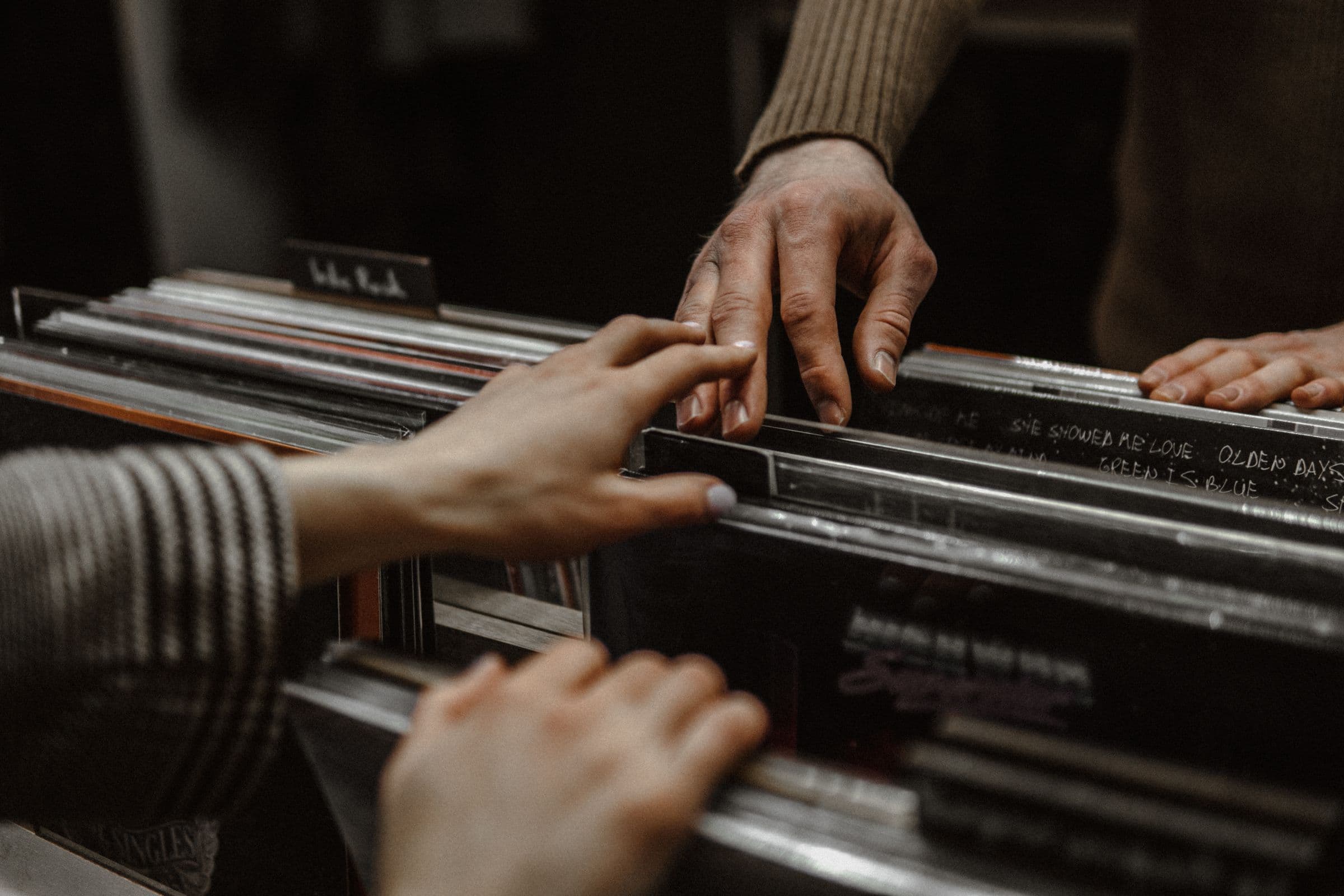Two people flipping through vinyl records in a record store crate