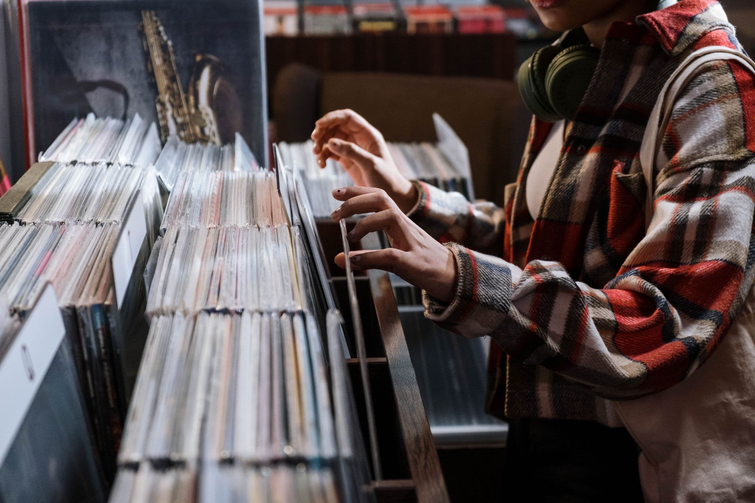 Person in headphones flipping through vinyl records in a record store