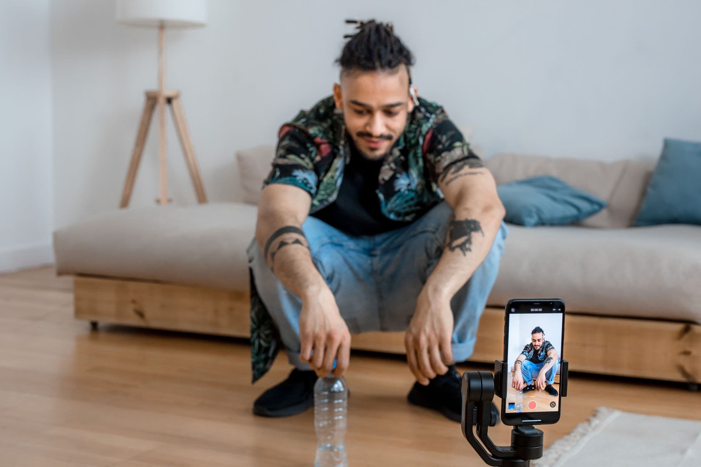 Man filming himself with a phone on a small tripod in his living room