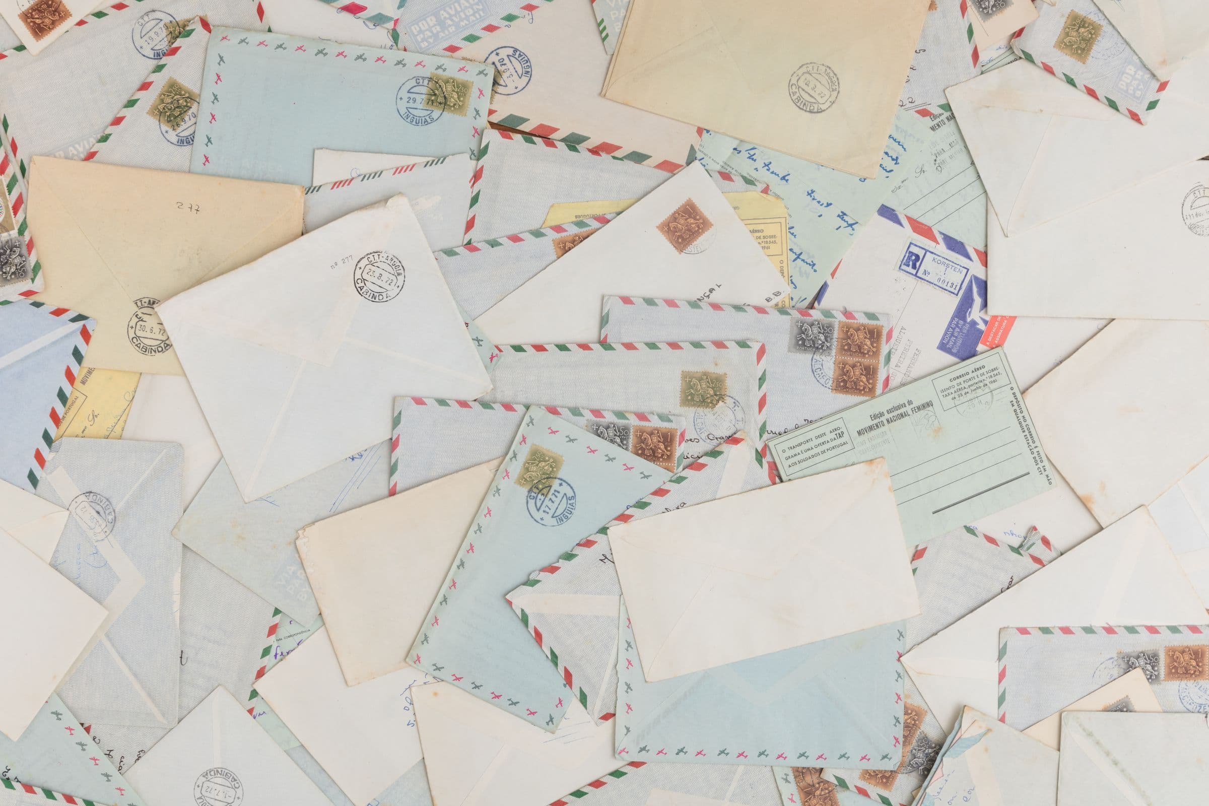 Pile of old airmail envelopes and postcards covered in stamps